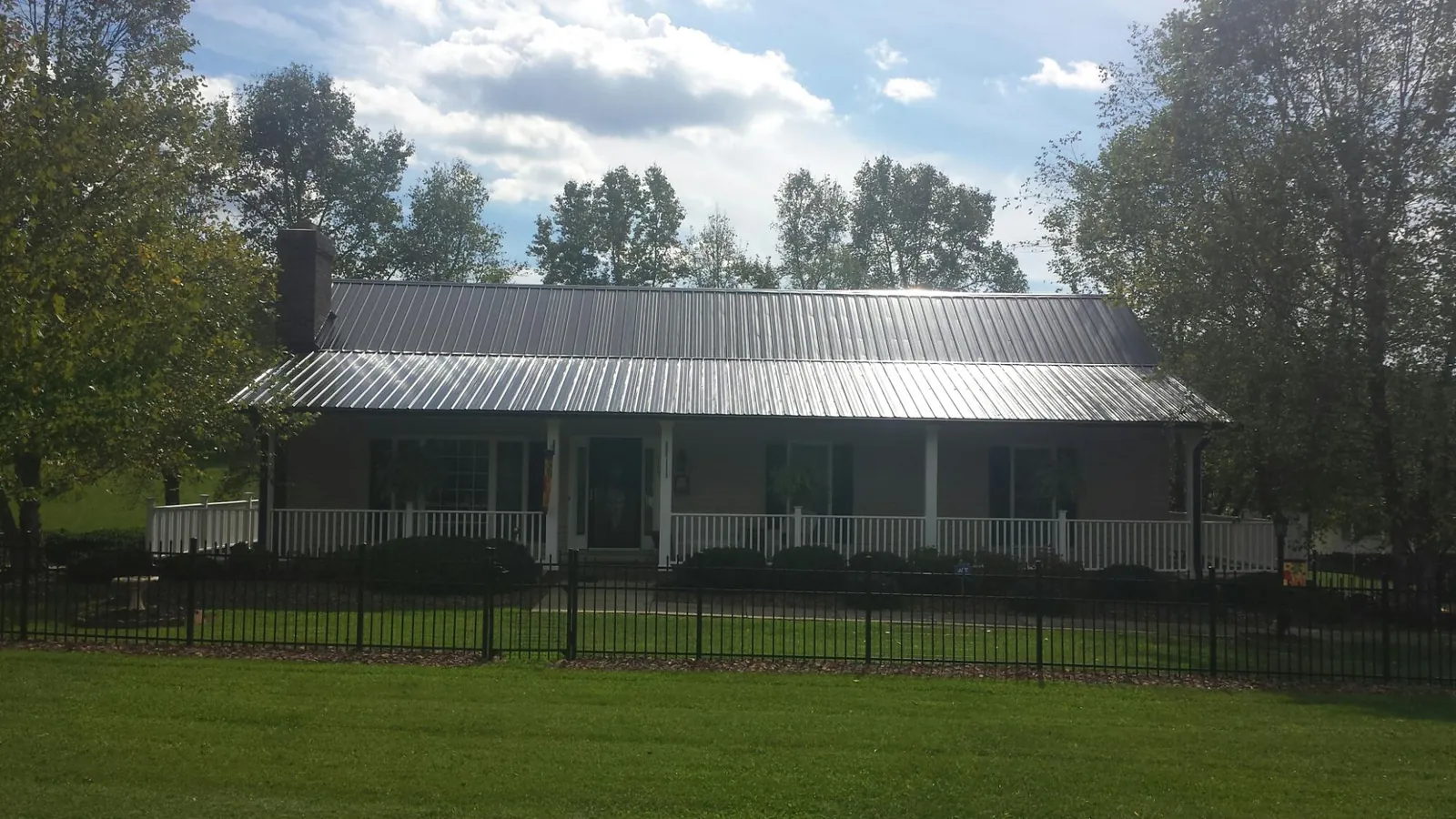 Gray metal roof on a brick ranch with a full width front porch — Gutter Guard Installation work by our crew in Hewitt