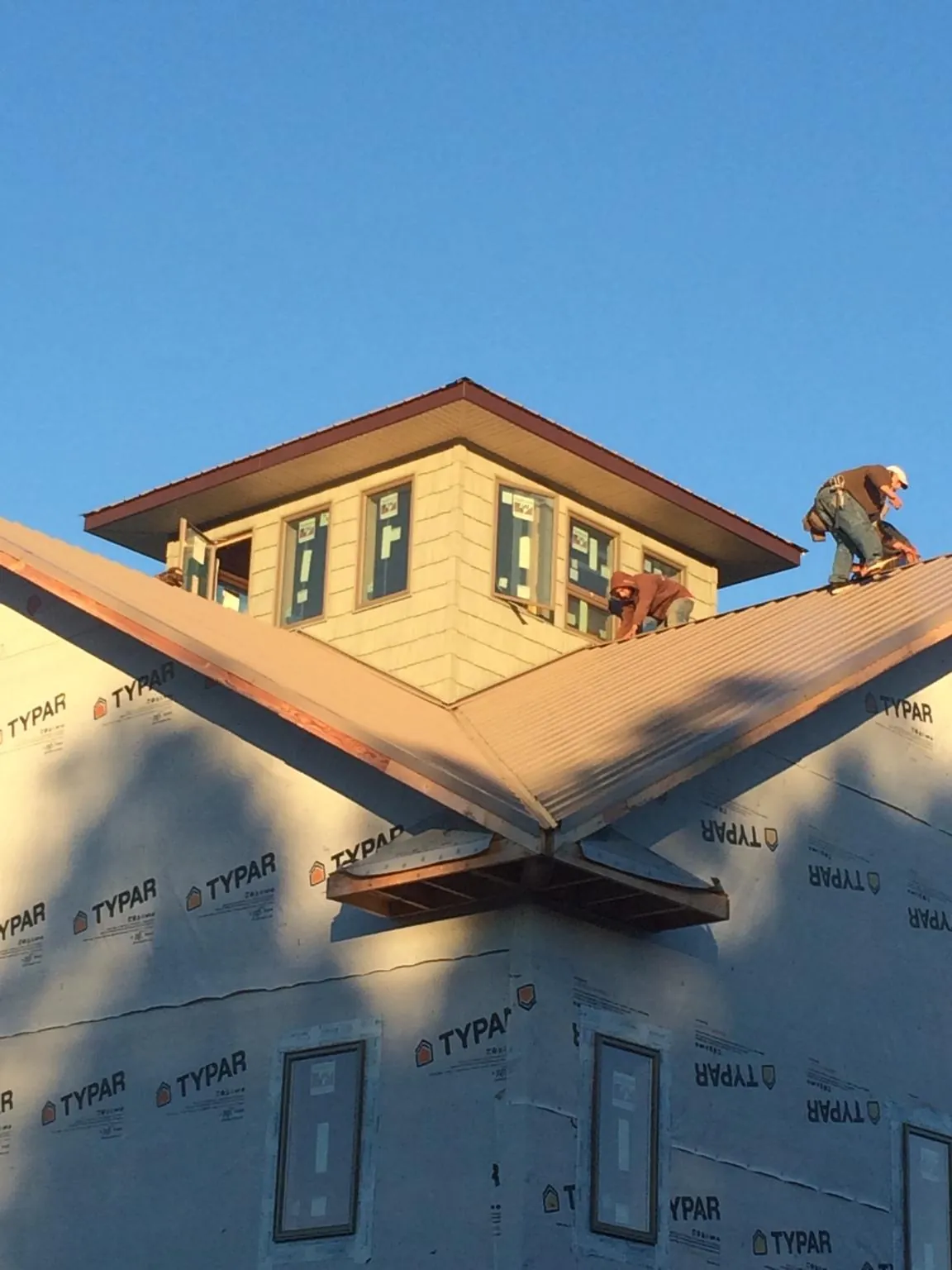 Roofers working around a rooftop cupola on a new metal roof at sunset — Roof Waterproofing in Hewitt by Roofing Brothers